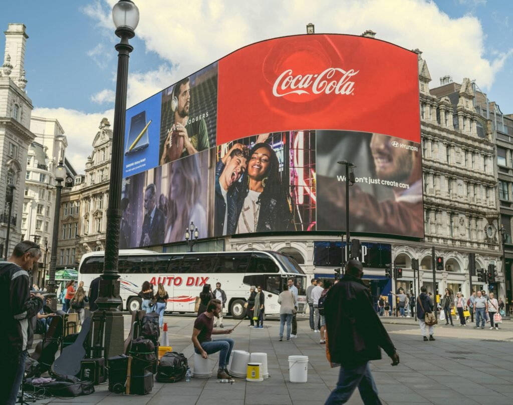 Tourists and buskers at Piccadilly Circus under iconic billboards in London, a center of urban life and commerce.