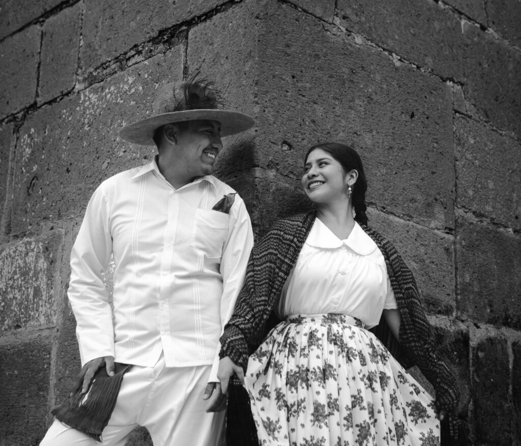Black and white portrait of a smiling couple in traditional Mexican attire in Oaxaca.