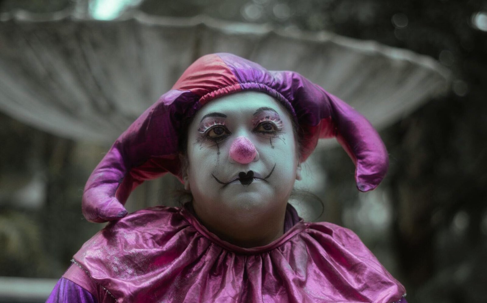 A dramatic portrait of a sad clown in a vintage costume set outdoors in Mexico City.